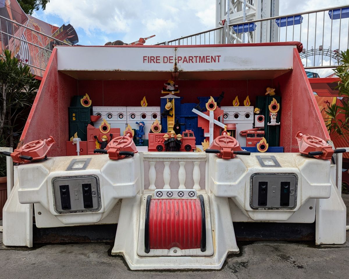 Foto von einem alten Feuerwehr-Spiel auf dem Wiener Prater. Ein Automat, an dem man mit Wasser auf bestimmte Ziele in einem Feuer-Szenario zielen kann.