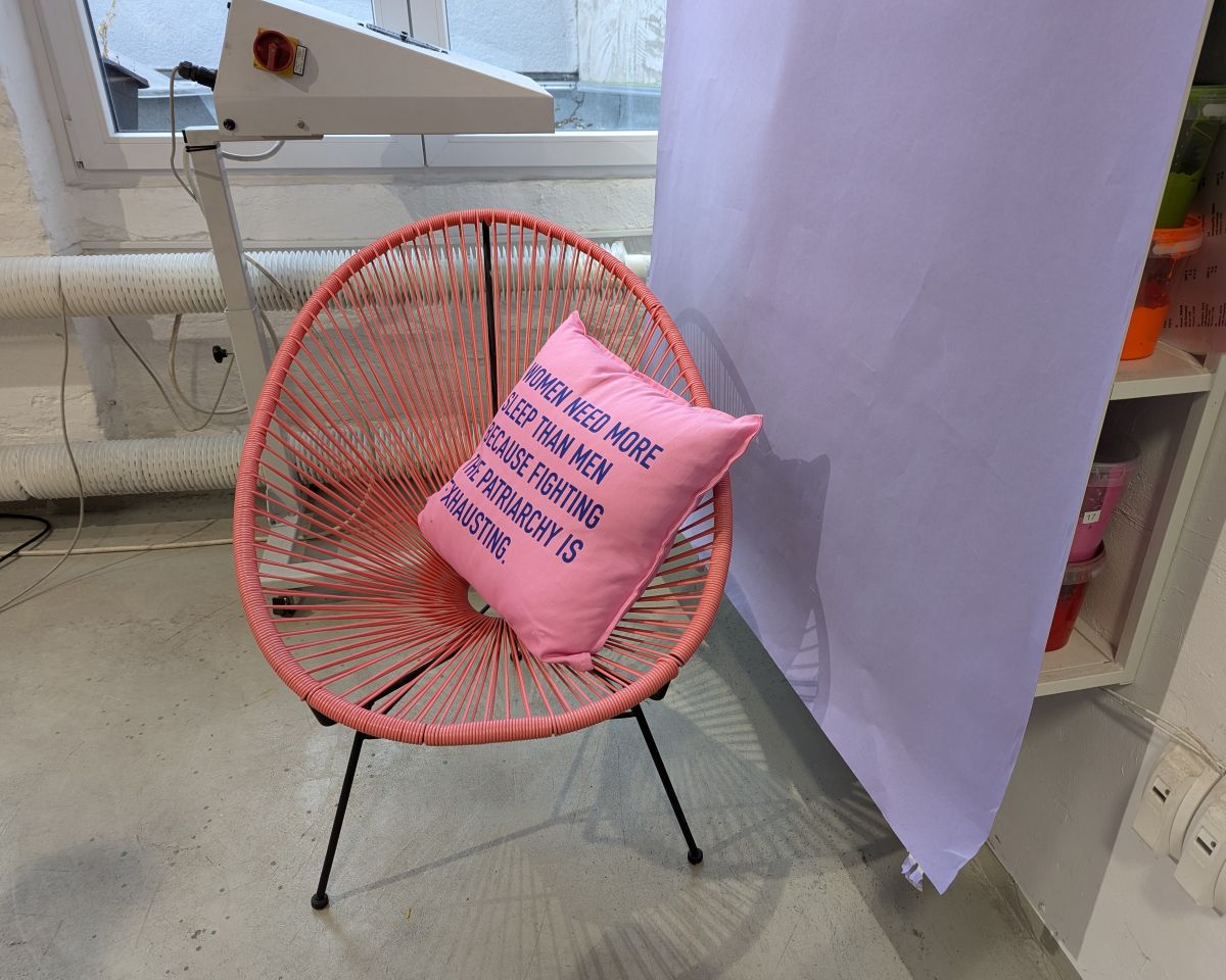 Bild von einem String-Chair mit einem Kissen, das mit Siebdruck bearbeitet wurde. Darauf der Slogan "Women need more sleep than men, because fighting the patrairchy is exhausting.