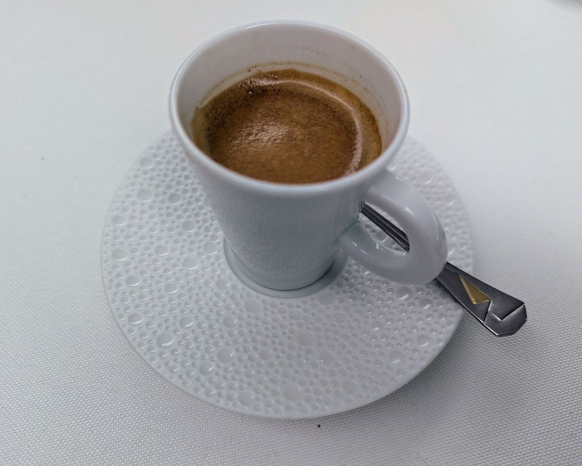 Eine Tasse Espresso in einer ausgewählten Tasse mit Blubber-Muster und einem Kaffeelöffel, der eine Origami-Faltung andeutet.