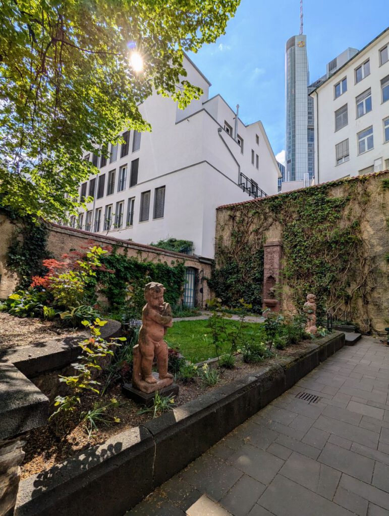 Blick in den Garten des Goethehauses im Vordergrund, der Commerzbank Tower im Hintergrund.