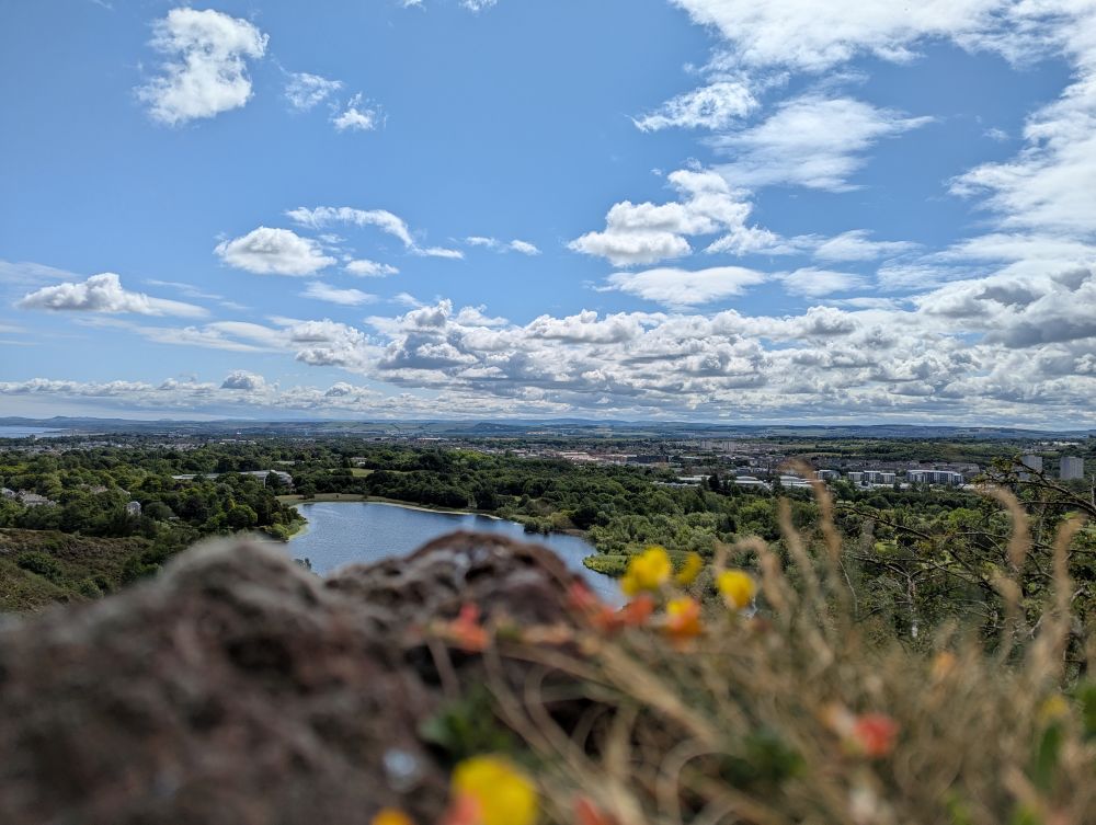 Fernblick von Arthurs Seat aus: Ein Himmel voller Wolken, in der Ferne die Highlands und unter uns ein schottisches Loch.