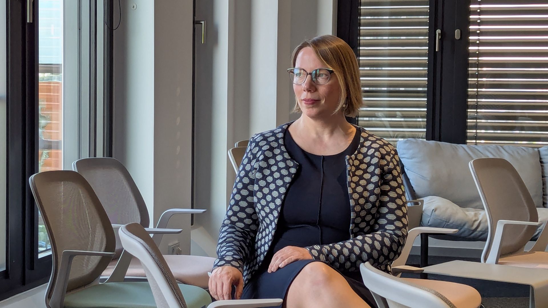 Astrid Schewe beim Fotoshooting für die Working@Office. Ich sitze entspannt in einem modularen Konferenzraum und schaue aus dem Fenster.