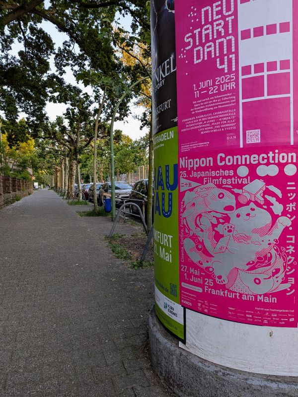 Noch ein Bild des Festivalplakats an einer Litfaßsäule.